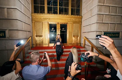 Photographers capturing a model on the red-carpet steps at the entrance of a YFS venue