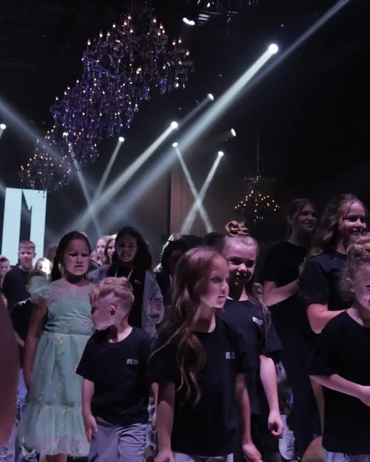 Participants on the YFS stage under chandeliers and stage lights